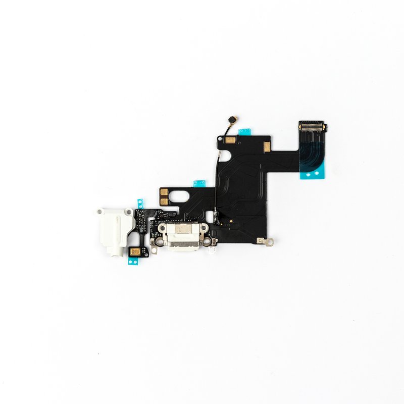 The complete iPhone 6 charging port flex laid out horizontally, white Lightning connector and headphone jack at the left and the ribbon connector at the right.
